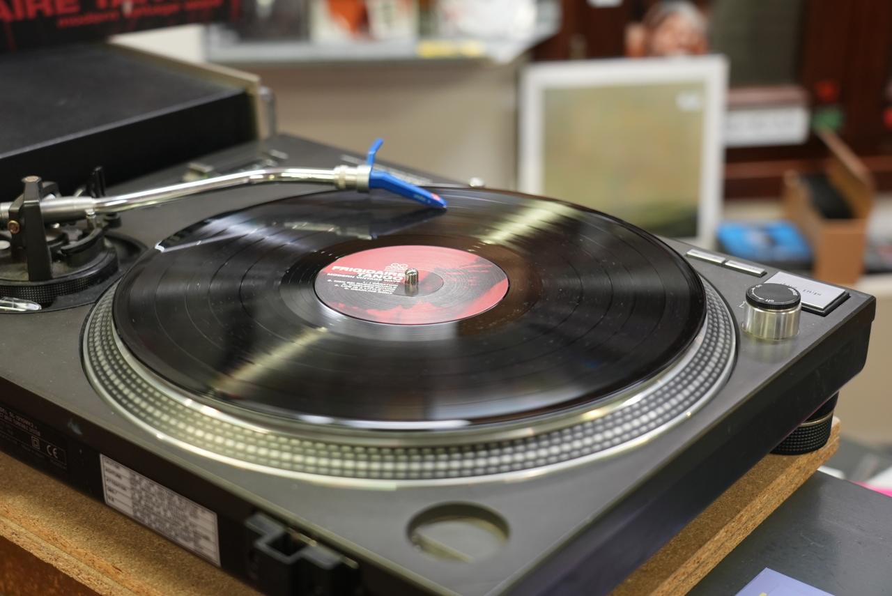 The Frigidaire Tango album spinning on a turntable inside the record shop